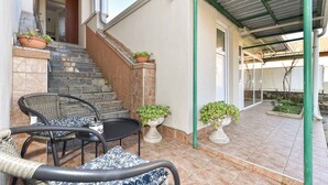 Un espace extérieur abrité, doté d’un escalier en pierre, de plantes en pot et de mobilier d’extérieur.