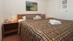 Una camera da letto con un letto, un comodino, una lampada e un quadro appeso al muro.