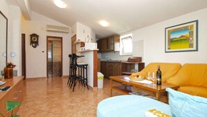 Un soggiorno con divano, tavolino e zona pranzo con sedie, e una cucina sullo sfondo.
