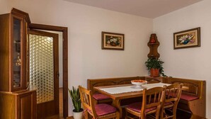 A dining area with a wooden table and chairs, a cabinet, and two framed floral paintings on the wall. - Holiday apartment with garden and barbecue (Banjole)