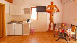 A kitchen with white cabinets, a sink, a small refrigerator, a coffee maker, and a window. - Holiday apartment with sea view (Pješćana Uvala)