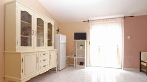 Eine geräumige Küche mit einem großen Schrank, einem Kühlschrank und einem kleinen Tisch mit einer Pflanze.