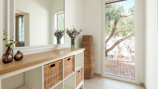 Een kamer met een houten console tafel, rieten manden en een grote spiegel.