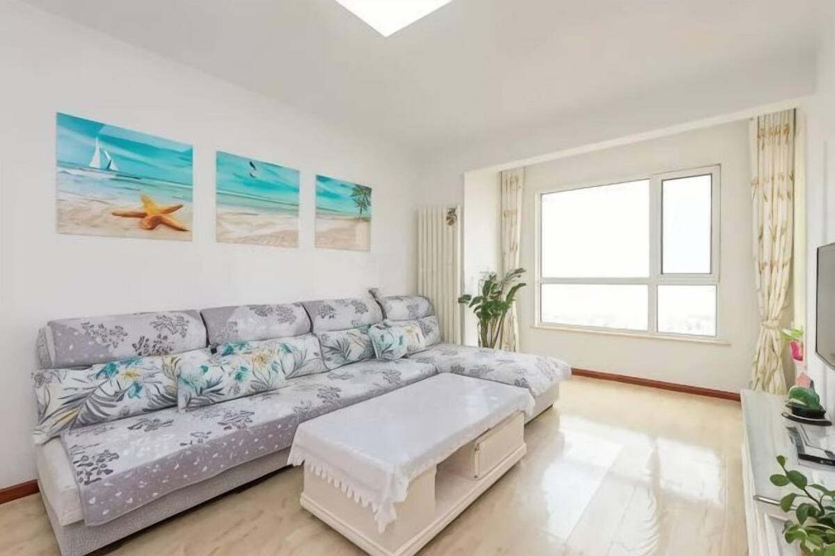 A living room with a sofa, a bench, and a large window.