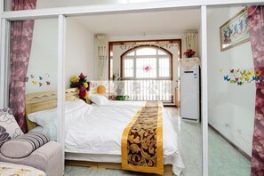 A hotel room with a bed, a sofa, a window with curtains, and a refrigerator. - Qingdao Golden Beach Chaoyang Seaview Apartment (Qingdao)