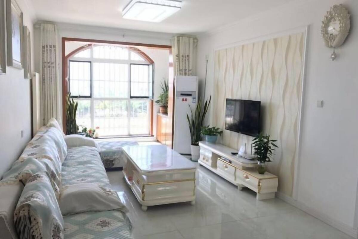 A living room with a sofa, a coffee table, a TV, and a refrigerator.