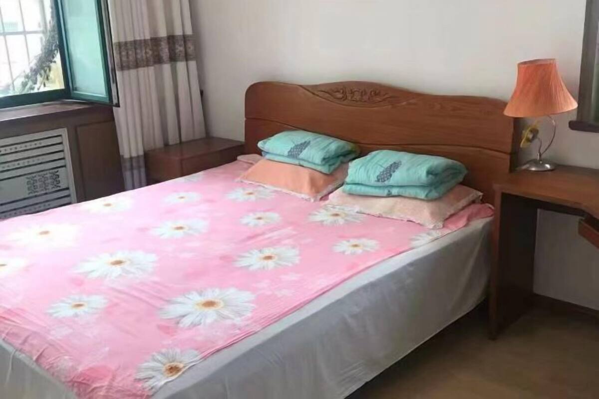 A bed with a floral bedspread, pillows, and a wooden headboard.