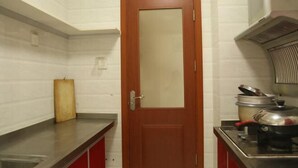 A kitchen with a wooden door, stainless steel countertops, a gas stove, and a pot on the counter. - Qingdao Golden Beach Chaoyang Seaview Apartment (Qingdao)