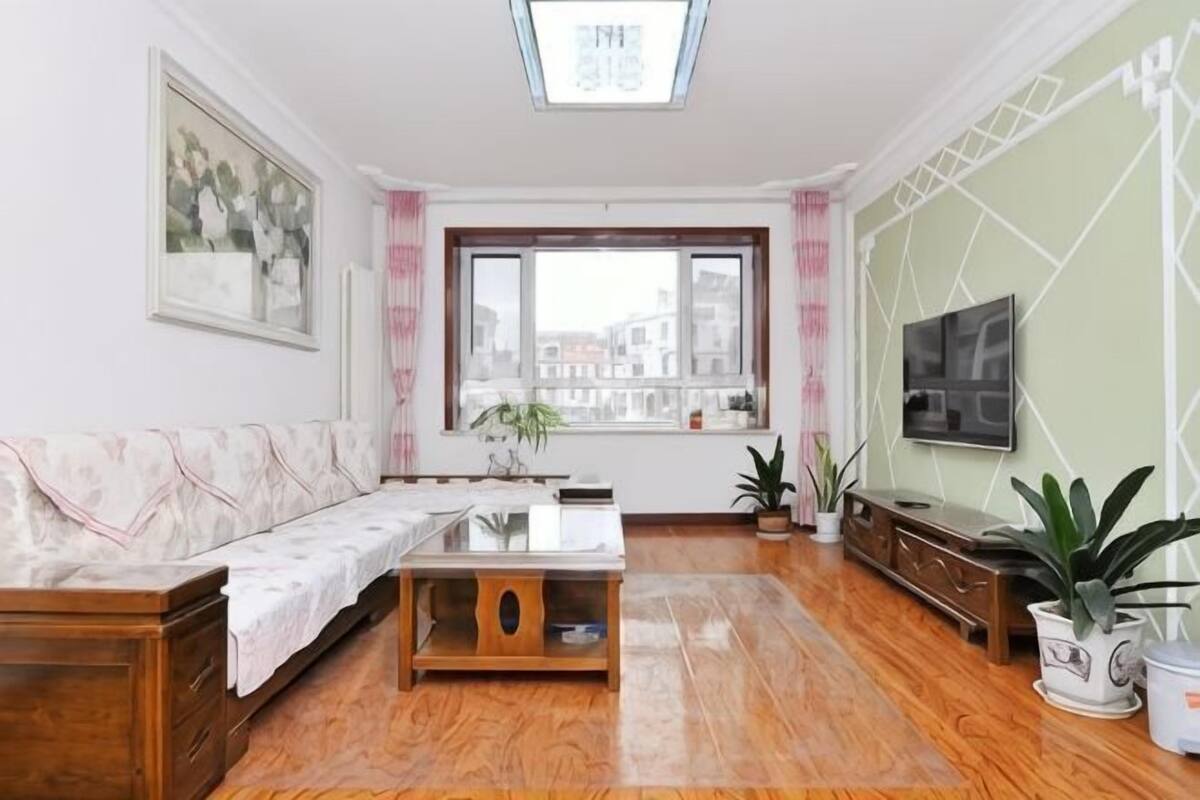 A living room with a sofa, a coffee table, a TV, and a window with a view.