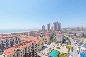 A residential area with multiple apartment buildings, a swimming pool, and a clear view of the sea. - Qingdao Golden Beach Chaoyang Seaview Apartment (Qingdao)