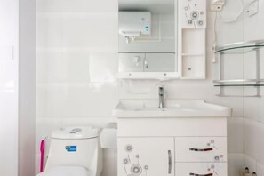 A modern bathroom with a toilet, sink, and mirror. - Qingdao Golden Beach Chaoyang Seaview Apartment (Qingdao)