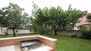 An outdoor barbecue area with a brick grill and a metal bowl.