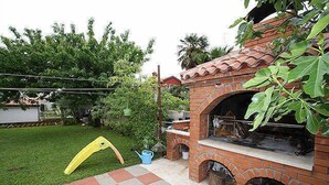 A brick outdoor kitchen with a grill, a yellow slide, and a blue watering can.