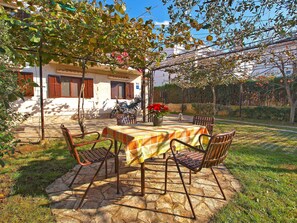 A patio with a table and chairs, a motorcycle, and a small dog.