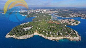 Eine Luftaufnahme einer Küstenstadt mit einem Yachthafen, grünen Hügeln und klarem, blauem Wasser.