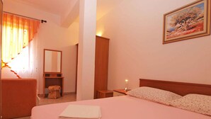 Ein Hotelzimmer mit einem Bett, einem Nachttisch mit Lampe, einem kleinen Tisch mit Stuhl, einem Spiegel und einem Bild an der Wand.