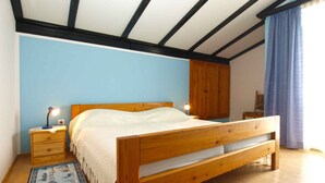 Une chambre à coucher avec un lit en bois, une table de chevet avec une lampe, une armoire et un rideau bleu.