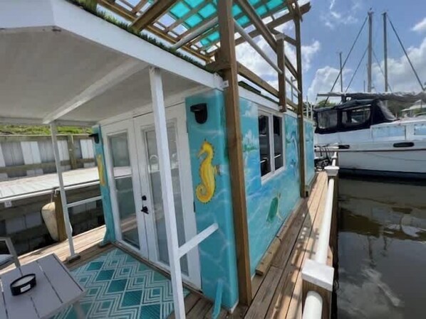 A boat with a covered deck, a glass door, and a seahorse mural.