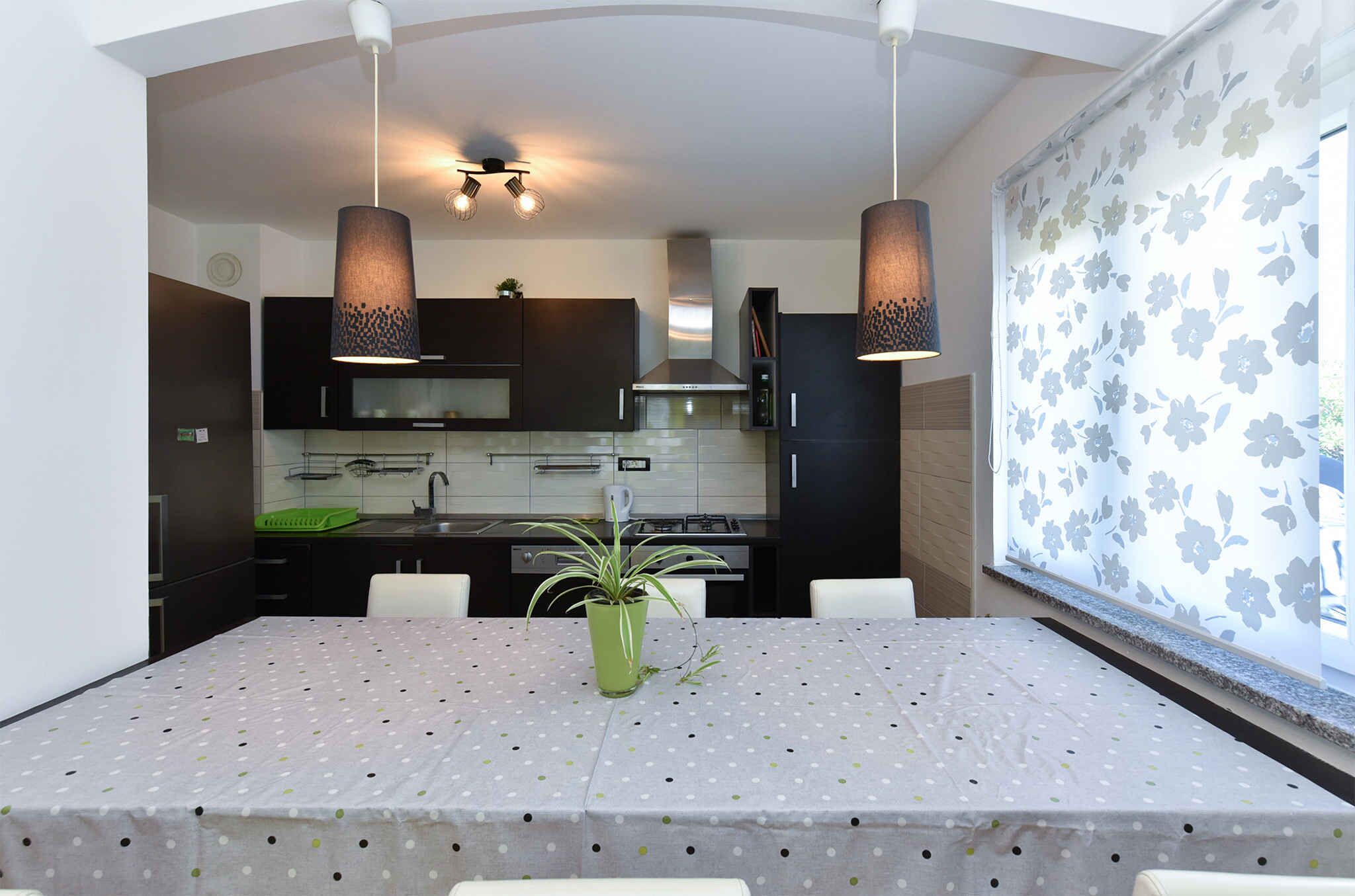 A modern kitchen with dark cabinets, a central island, and pendant lighting.