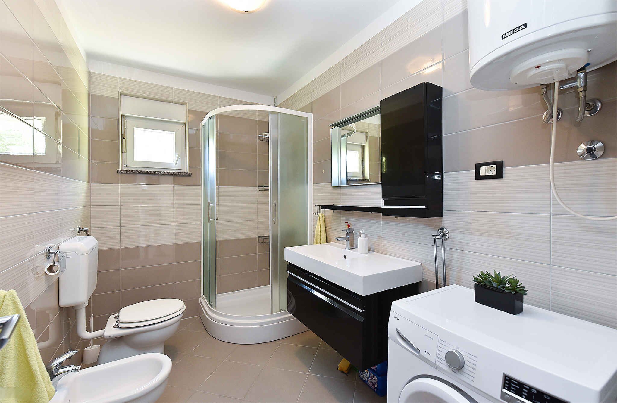 Une salle de bain moderne équipée d’une douche à parois de verre, de toilettes, d’un bidet, d’un lavabo et d’un lave-linge.