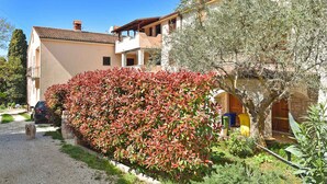 A residential building with a paved driveway, a well-maintained hedge, and a tree. - Holiday apartment with garden and air conditioning (Medulin)