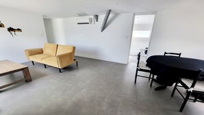Un salon moderne avec un canapé beige, une table basse en bois et une table à manger avec des chaises.