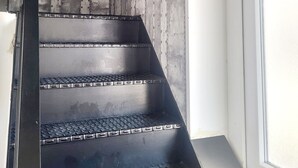 Un escalier avec des marches en métal et un mur en béton avec des rivets.