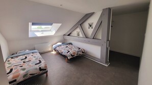 Une chambre à coucher de taille réduite, dotée d’un puits de lumière, de deux lits et d’une armoire intégrée.