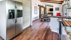 Eine moderne Küche mit einem Edelstahlkühlschrank, Holzboden und Holzbalkendecke.