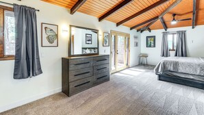 Ein Schlafzimmer mit Holzboden, einem großen Bett, einer Kommode und einer Schiebetür.