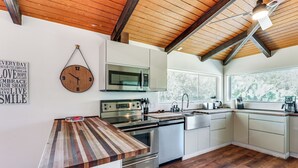 Eine moderne Küche mit Holzboden, Edelstahlgeräten und einer Holz-Wanduhr.