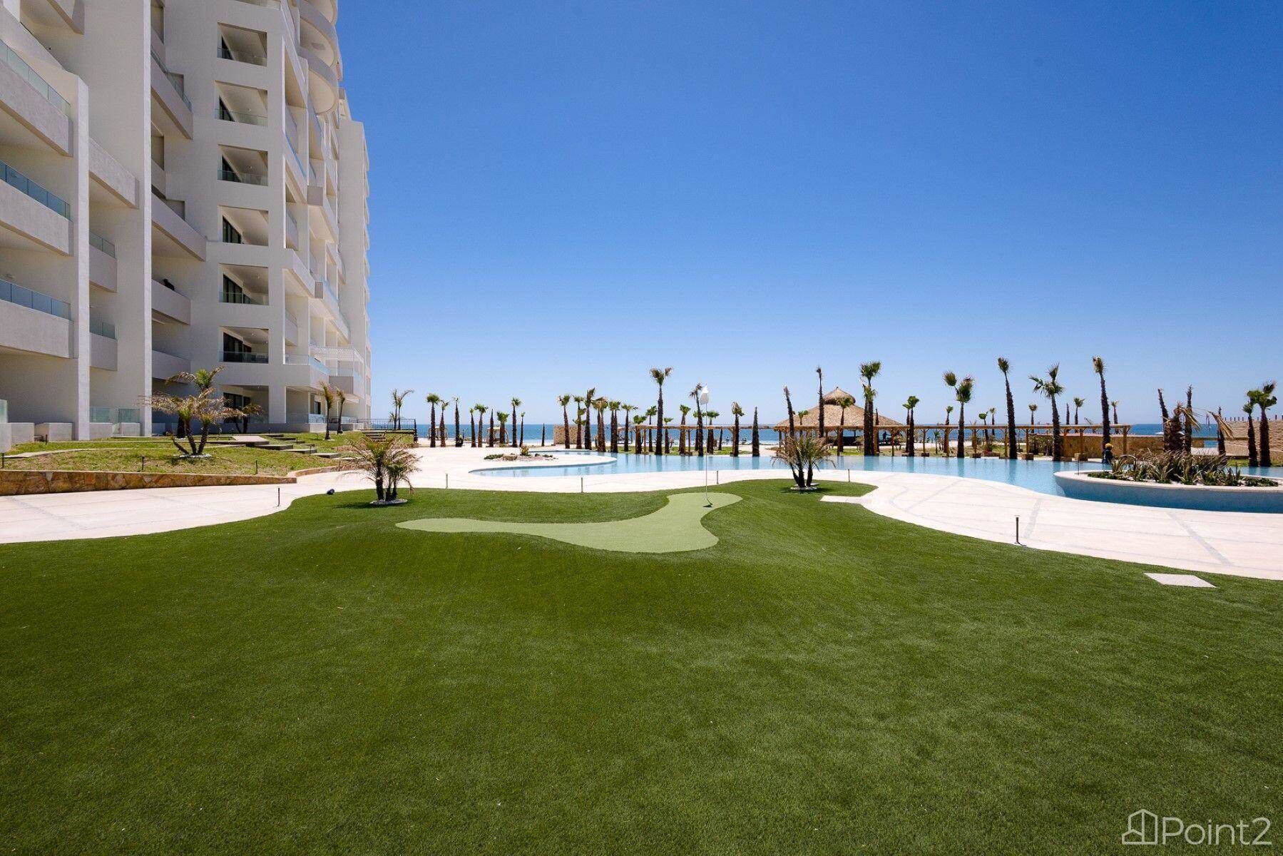A resort with a swimming pool, palm trees, and a large building with multiple balconies.