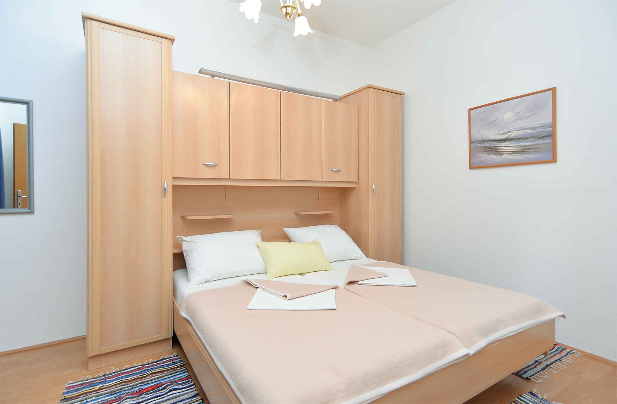 Una camera da letto con un letto, un armadio, un quadro e un lampadario.