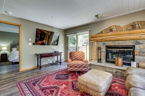 A living room with a fireplace, a large rug, a sofa, and a television.
