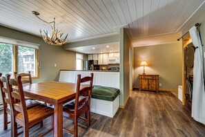 A dining area with a wooden table and chairs, a kitchen with white cabinets, and a laundry area with a washing machine. - Walk to Beaver Creek Village: Cozy Condo! (Beaver Creek)