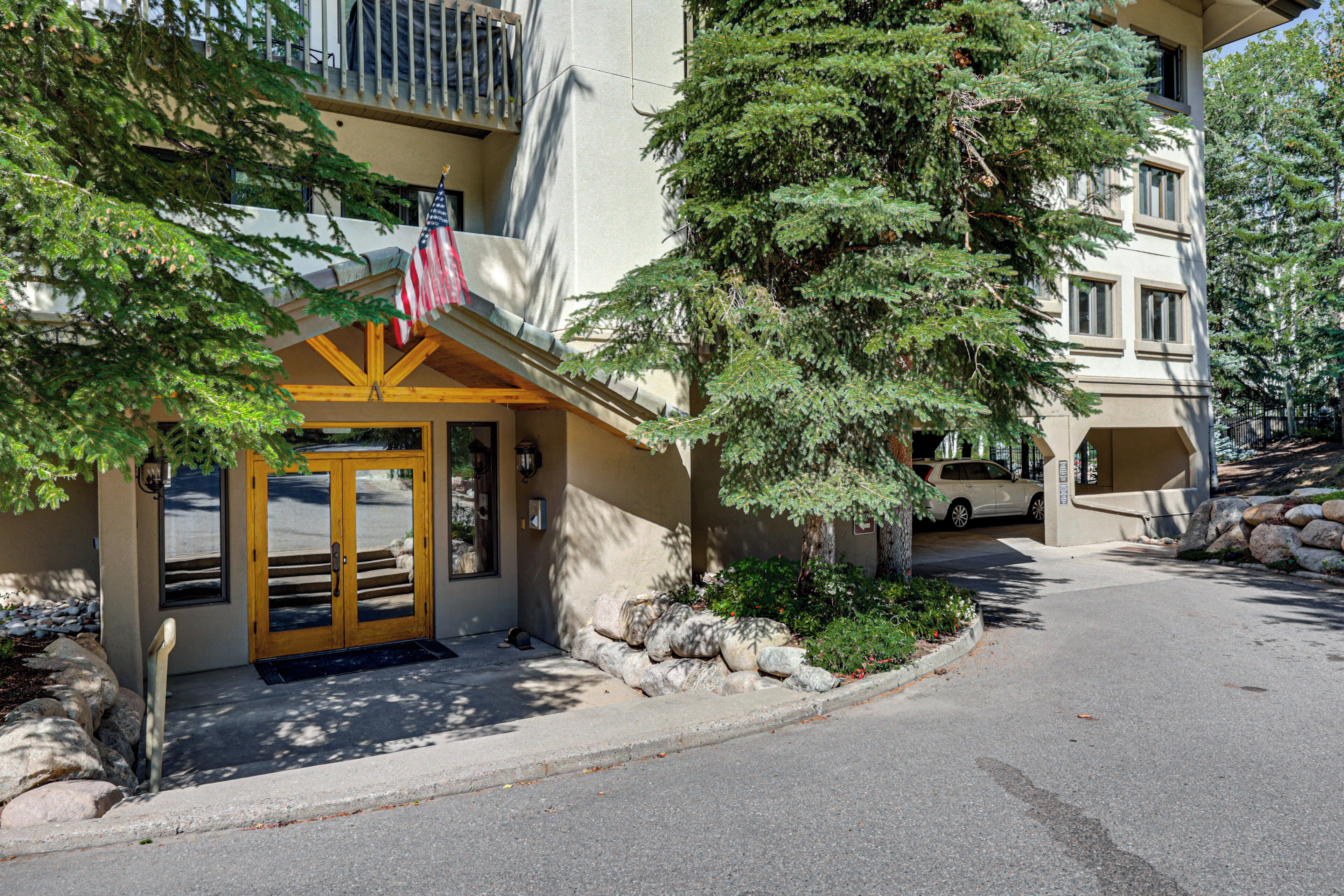 A hotel entrance with a wooden facade, a flag, and a stone pathway leading to the door.