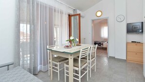 A dining area with a table, chairs, and a TV mounted on the wall. - Holiday apartment with garden and barbecue (Fažana)
