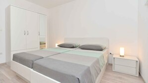 A bedroom with a bed, bedside tables, and a wardrobe. - Holiday apartment with garden and barbecue (Fažana)
