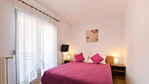 A bedroom with a bed, a nightstand, a lamp, a radiator, and a window with curtains. - Holiday apartment with air conditioning and outdoor pool (Poreč)