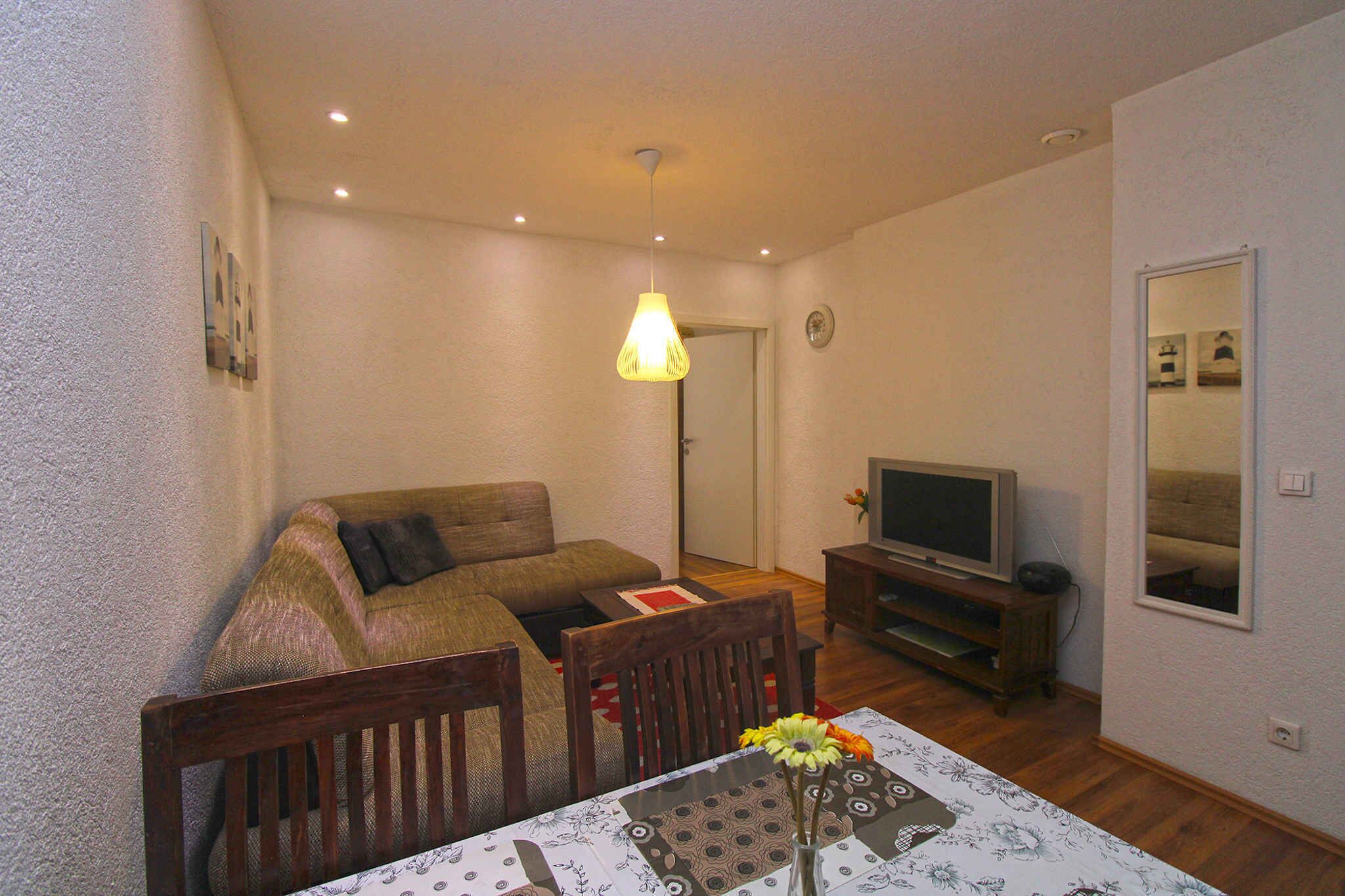 A living room with a sofa, TV, dining table, and chairs.