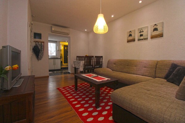 A living room with a sofa, a coffee table, a TV, and a red polka dot rug.