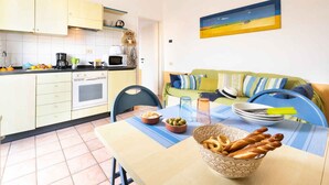 Una cucina compatta con zona pranzo, divano e un quadro appeso al muro.
