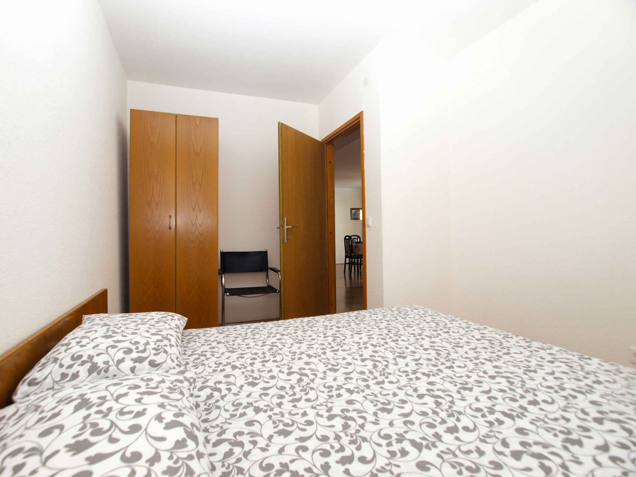 A bedroom with a bed, a wooden wardrobe, and a chair in the corner.