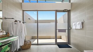 Une salle de bain moderne avec une porte en verre donnant sur un balcon, un porte-serviettes et un panier en osier.