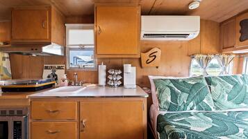 Une cuisine compacte pour camping-car, avec des placards en bois, un four à micro-ondes, un évier et une machine à café.