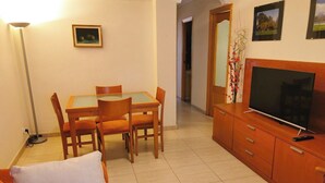 A living room with a dining table, chairs, a sofa, a TV, and a cabinet. - Centro Cerca Playa (Benidorm)