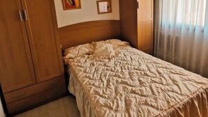 A bedroom with a bed, wooden wardrobe, ceiling fan, and curtains. - Centro Cerca Playa (Benidorm)