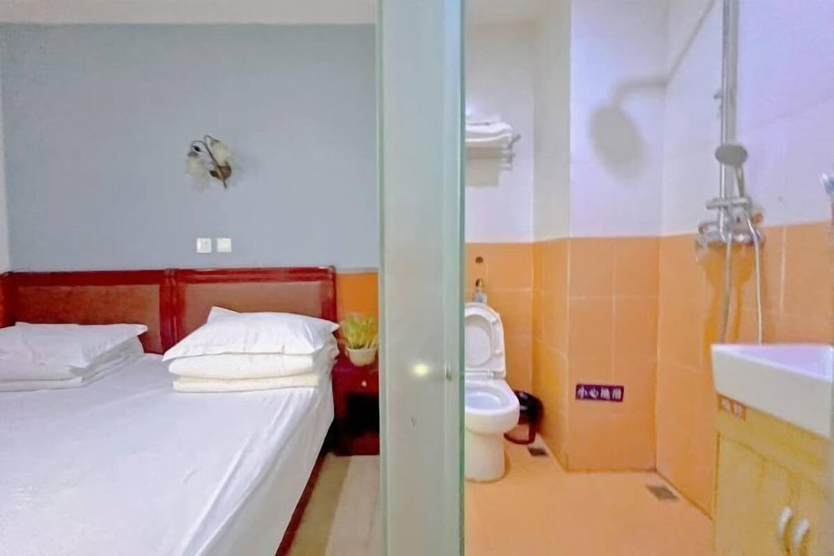 Quarto com duas camas, chuveiro, vaso sanitário e pia.