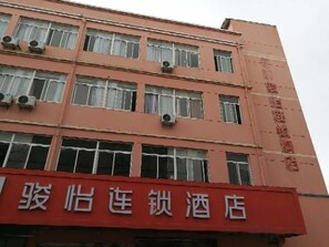 A multi-story building with a red sign indicating a hotel. - Junyi Chain Hotel (Haiyan Qiyuan Chengbei East Road) (Haiyan)