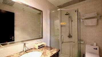 A bathroom with a sink, mirror, shower, and toilet.